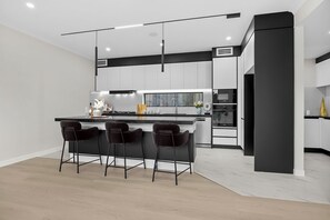 Eine moderne Küche mit einer zentralen Kochinsel, Barhocker und einem eingebauten Backofen.