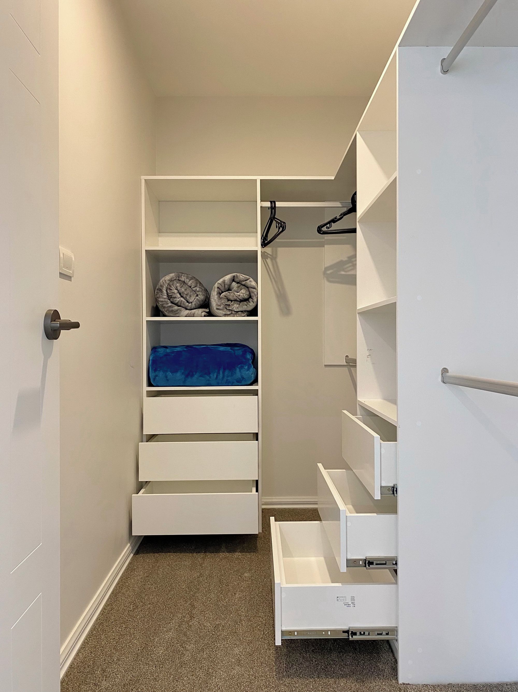 A walk-in closet with open shelves, a blue storage box, and a white door.