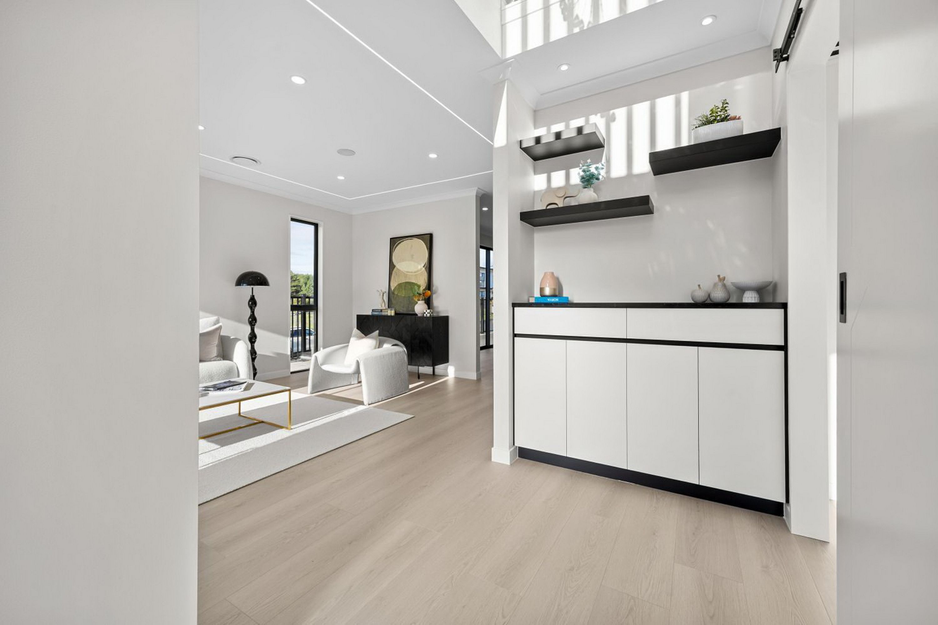 A modern interior with a kitchen area featuring white cabinetry, a black countertop, and decorative items.