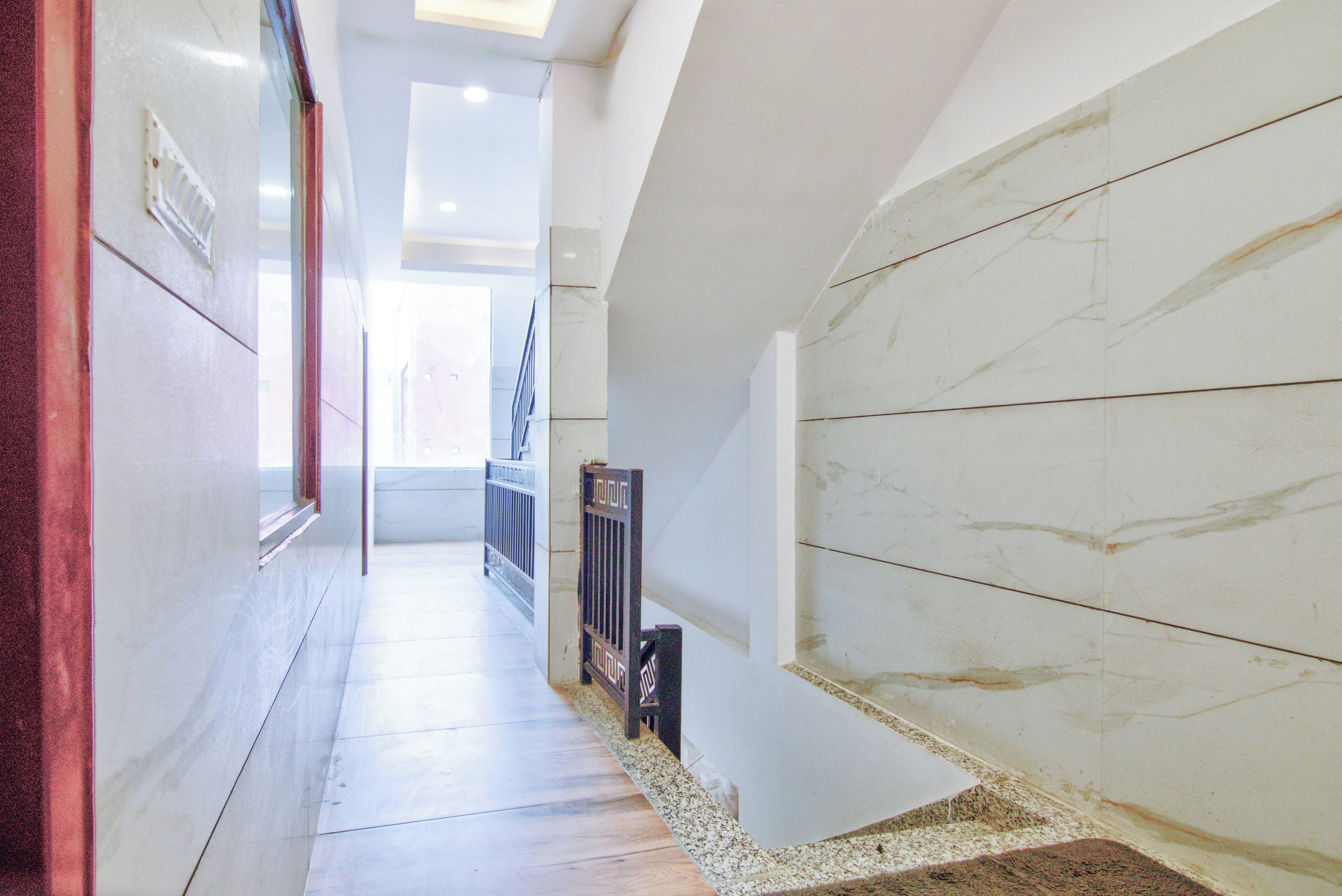 Un pasillo con paredes de mármol y suelo de madera, que conduce a una escalera.