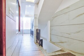 A hallway with marble walls and a wooden floor, leading to a staircase.