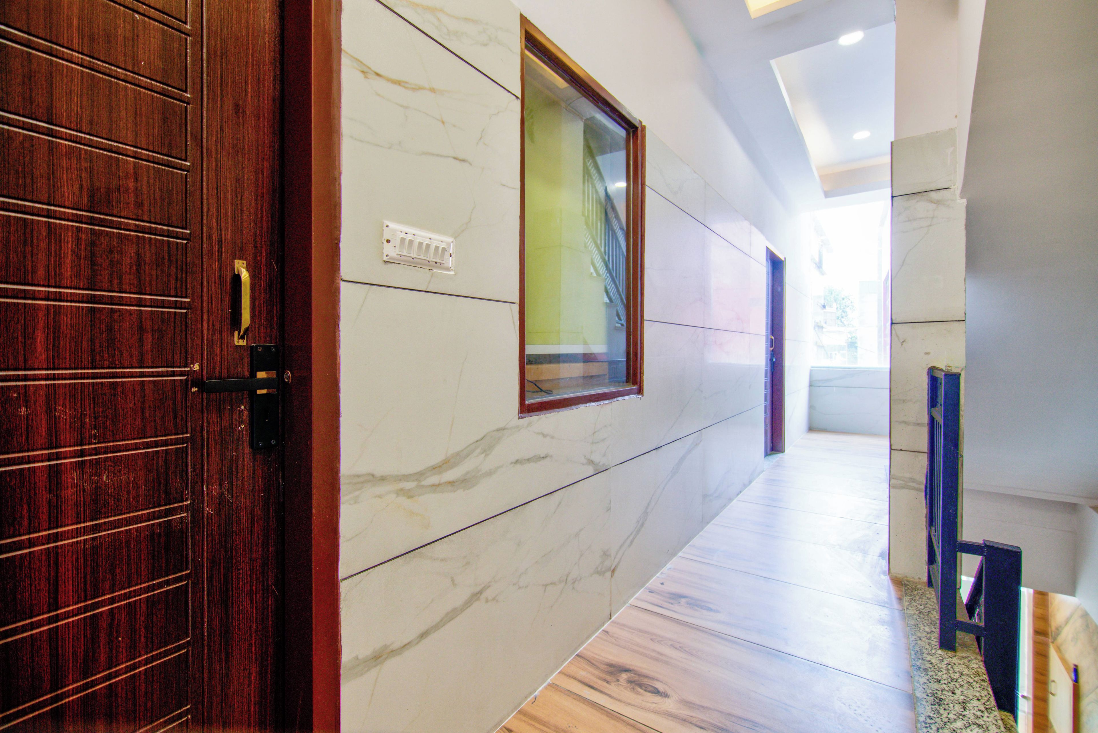 Un pasillo con una puerta de madera, una pared de mármol y una ventana.
