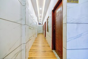 A hallway with marble walls, wooden flooring, and a door with a 'NO SMOKING' sign.