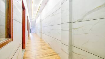 Un pasillo con paredes de mármol y suelo de madera que conduce a un espacio interior luminoso.