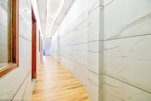 Un pasillo con paredes de mármol y suelo de madera que conduce a un espacio interior luminoso.