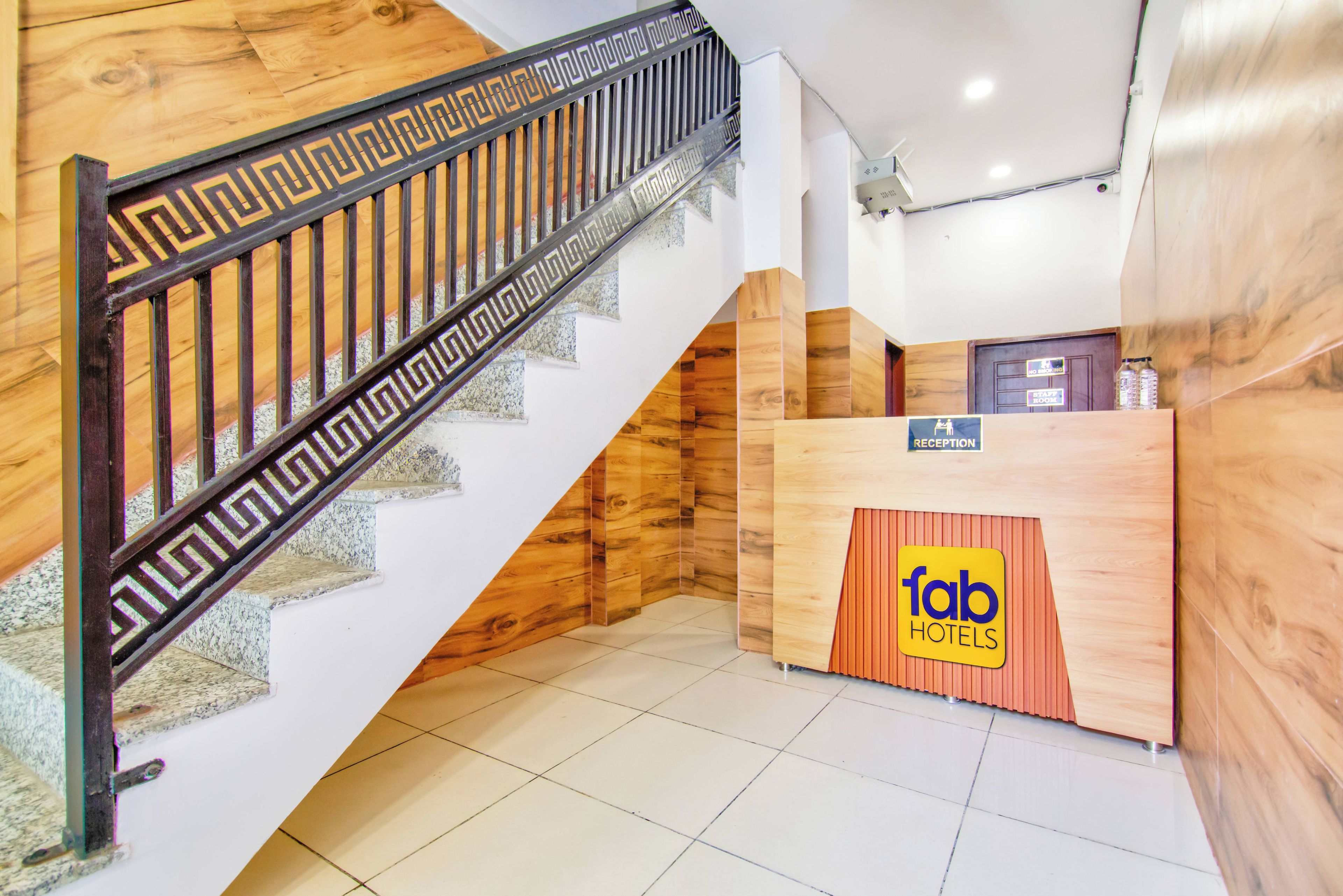 Un mostrador de recepción con un cartel que dice 'fab hotels' y una escalera con escalones de madera y barandilla de metal.