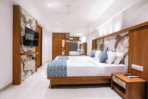 A modern bedroom with a large bed, a TV mounted on the wall, and a ceiling fan. - FabHotel Host Inn (Mumbai)