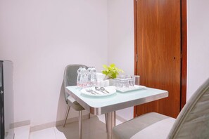 A small dining area with a table set for two, including water bottles, glasses, and cutlery. - FabHotel Host Inn (Mumbai)
