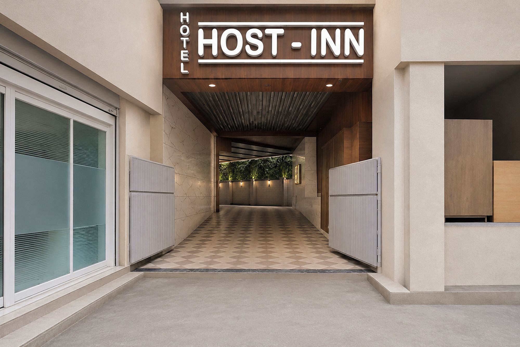 Un pasillo de hotel con piso a cuadros, techo de madera y un letrero que dice 'HOST - INN'.