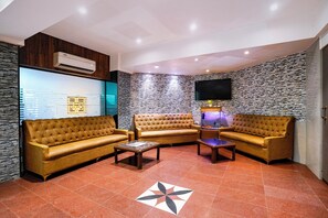 A modern living room with a sectional sofa, a flat-screen TV, and a decorative fish tank. - FabHotel Host Inn (Mumbai)