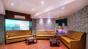 A modern living room with a stone wall, a flat-screen TV, and a large window with blinds. - Fabhotel Host Inn (Mumbai)