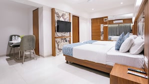 A modern hotel room with a large bed, a desk with a chair, a flat-screen TV mounted on the wall, and a ceiling fan. - Fabhotel Host Inn (Mumbai)