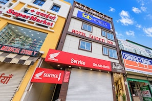 Un edificio de varios pisos con el nombre 'Hotel Jagruti Inn' en la planta superior, un supermercado en la planta baja y una farmacia a la izquierda.