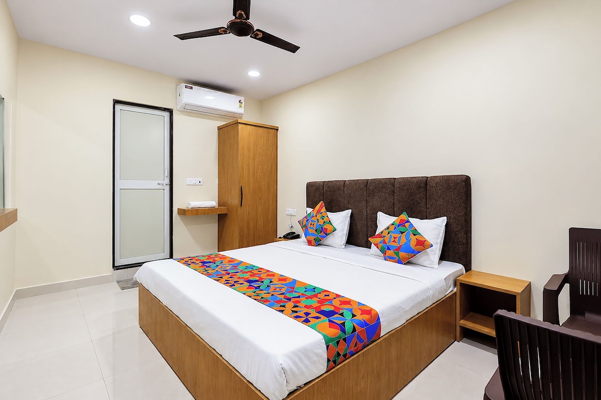 Una habitación de hotel con una cama, un armario, un ventilador de techo, un equipo de aire acondicionado y una silla.