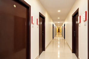 A hotel corridor with doors numbered 101 to 118, a tiled floor, and recessed ceiling lighting. - FabHotel Regal I (Hyderabad)