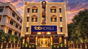 Um hotel com vários andares e um destaque para a placa 'fabHOTELS', apresentando uma fachada moderna com janelas uniformemente espaçadas e um design simétrico.