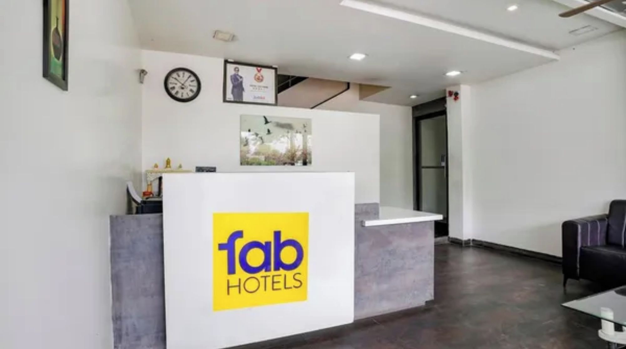 Una recepción con el logotipo de Fab Hotels, un reloj y un cuadro en la pared.
