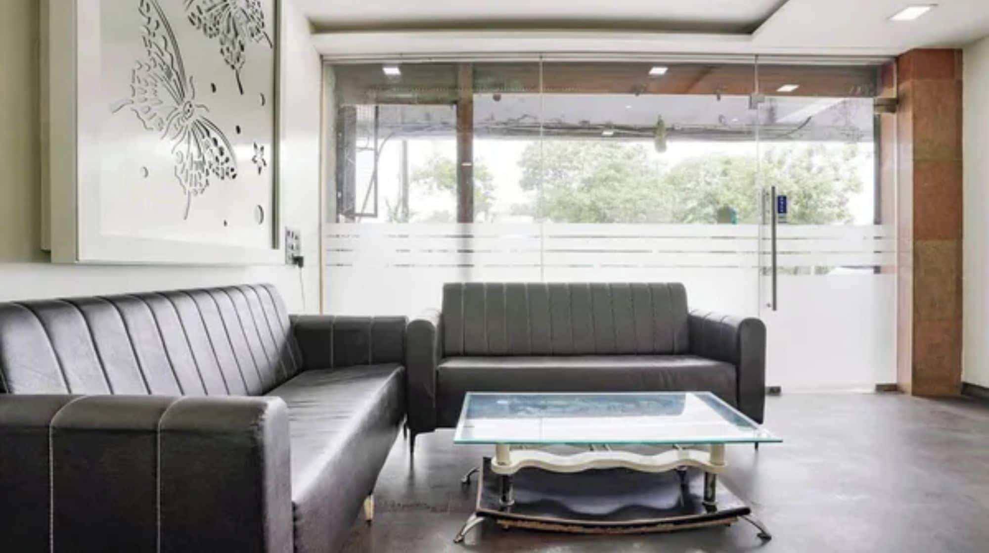 A modern waiting area with a glass-top table and two sofas.