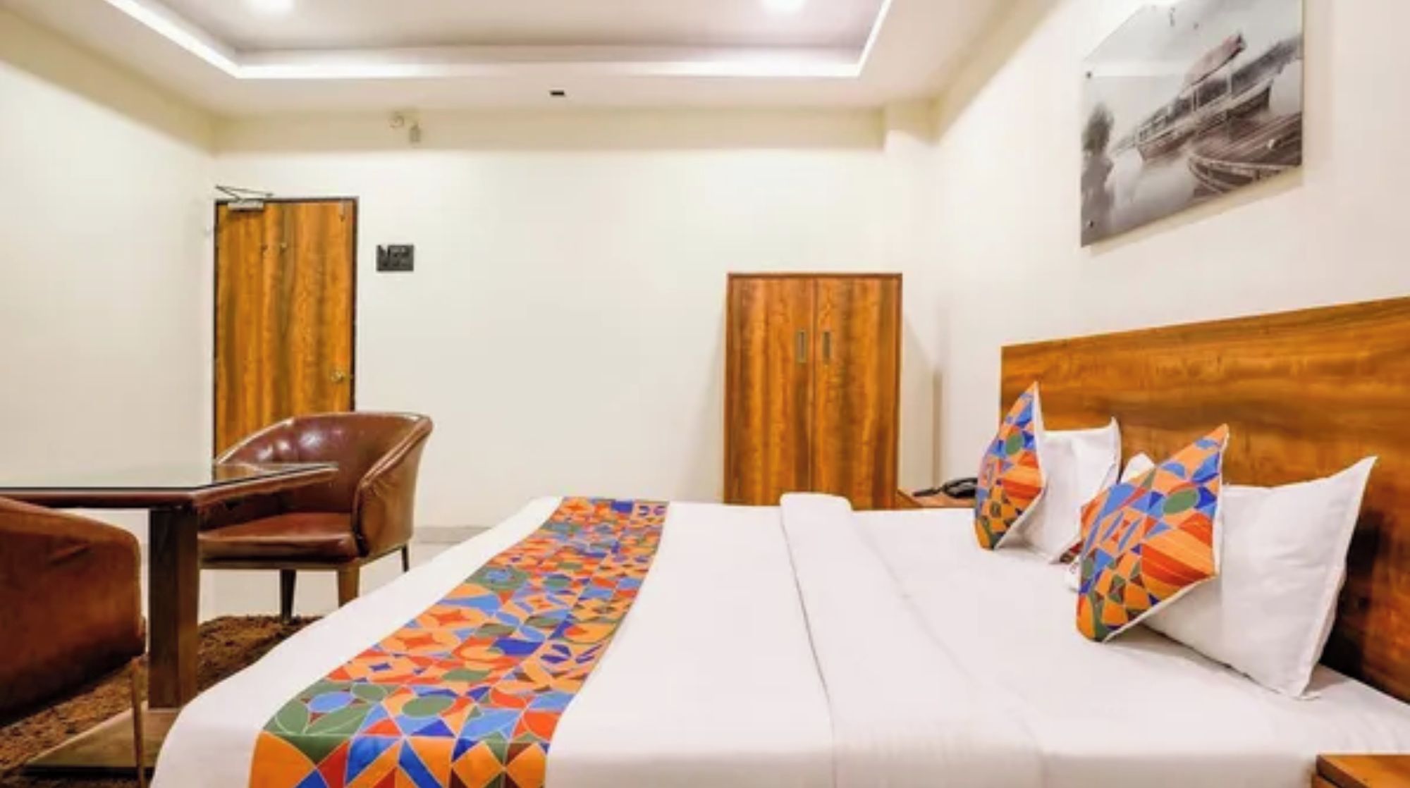 A hotel room with a bed, a desk, a chair, and two wardrobes.