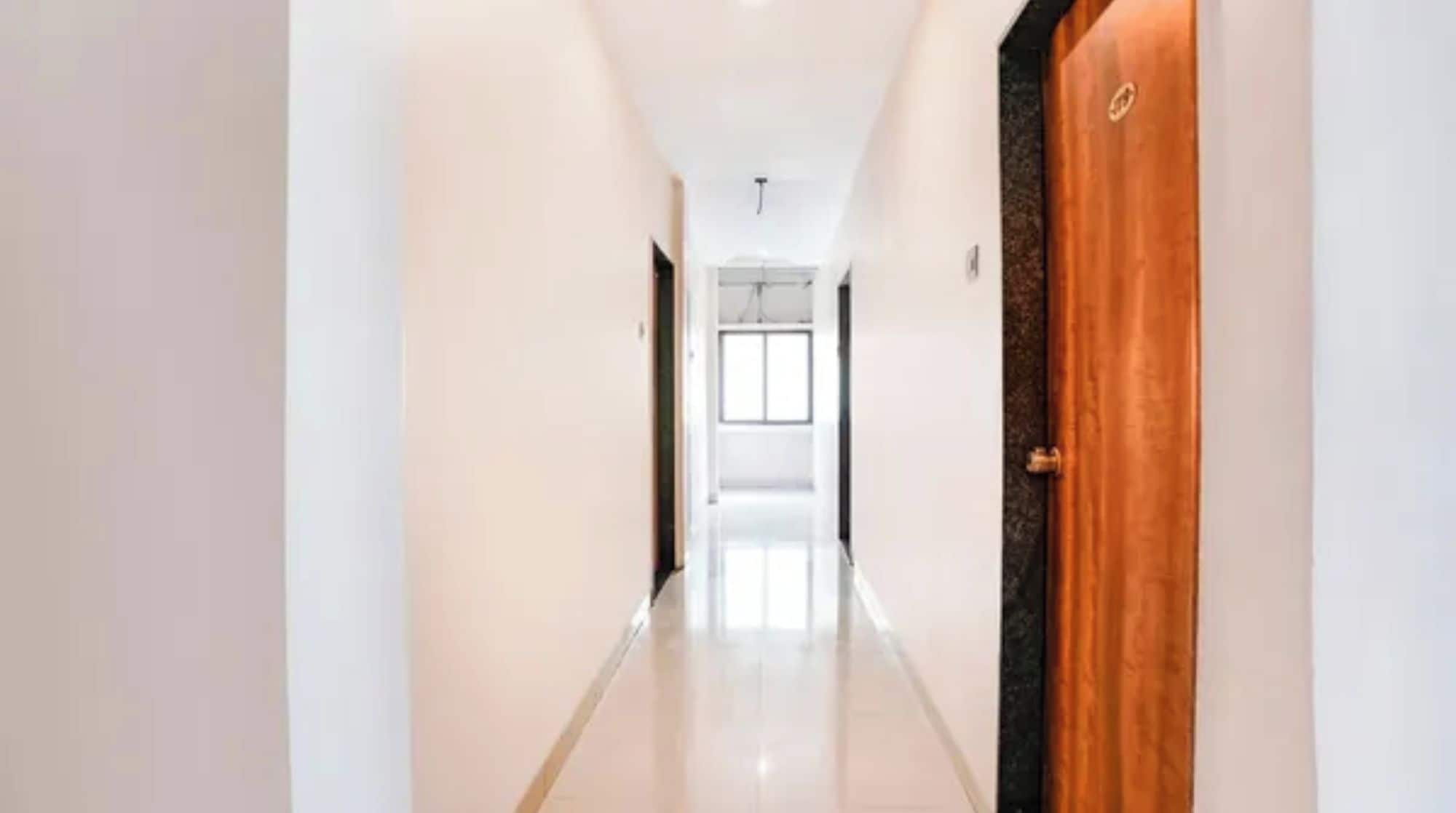 Un pasillo con una puerta de madera a la derecha, que da a una habitación con ventana.