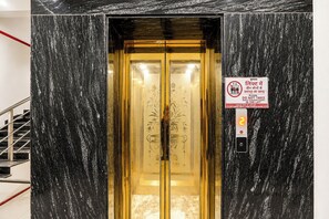 Un ascensor con puerta de vidrio, un cartel con instrucciones en varios idiomas y una pantalla digital que muestra el número 2.