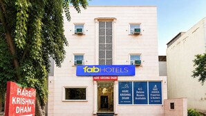 Fachada de hotel com placa indicando 'Hare Krishna Dharm' e 'Hare Krishna Dharm Hotels' sobre a entrada.