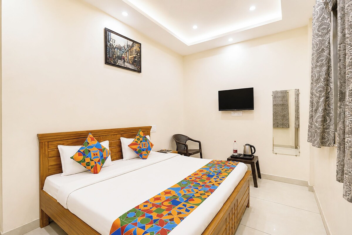 A hotel room with a bed, a television, a chair, a coffee maker, and a window with curtains.