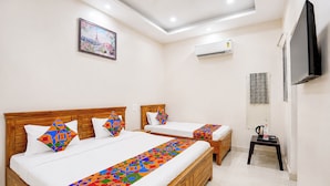 Quarto de hotel com duas camas, televisão, aparelho de ar condicionado e um quadro na parede.