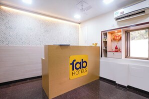 Una reception con il logo di 'fab hotels' e una finestra con un oggetto decorativo.