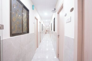Un corridoio con porte su entrambi i lati, pavimento piastrellato e soffitto con illuminazione incassata.