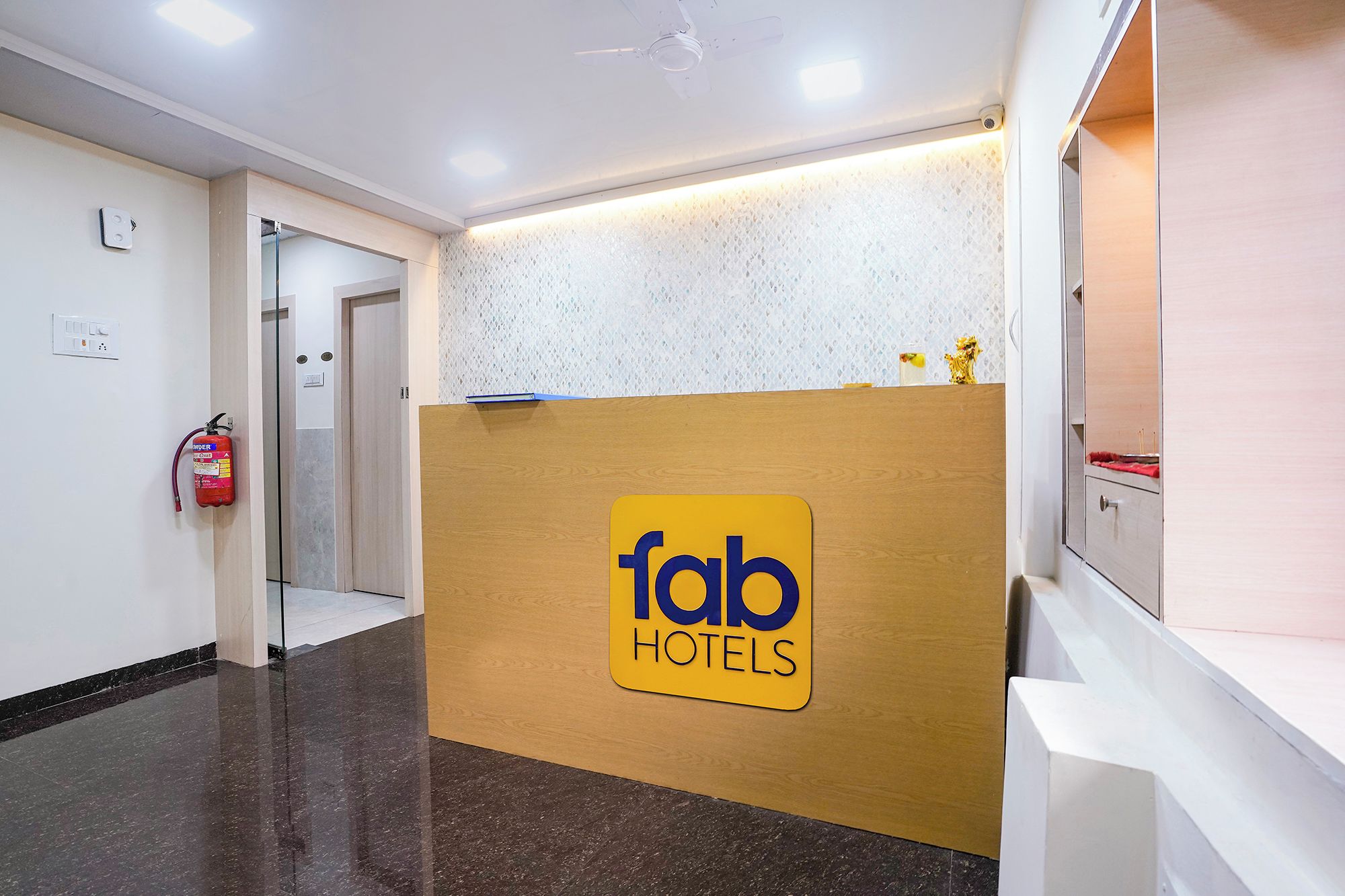 Uma área de recepção com um aviso para 'fab hotels' e um extintor na parede.