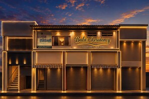 Un hotel di lusso con un cartello ben visibile, diverse porte per garage e una scalinata che conduce all'ingresso.