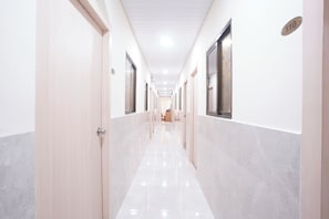 A hotel corridor with doors on both sides, a tiled floor, and a ceiling with recessed lighting. - FabHotel Bala'S Residency (Mumbai)