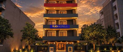 A multi-story hotel with a prominent 'fabHOTELS' sign, a gated entrance, and a landscaped front yard.