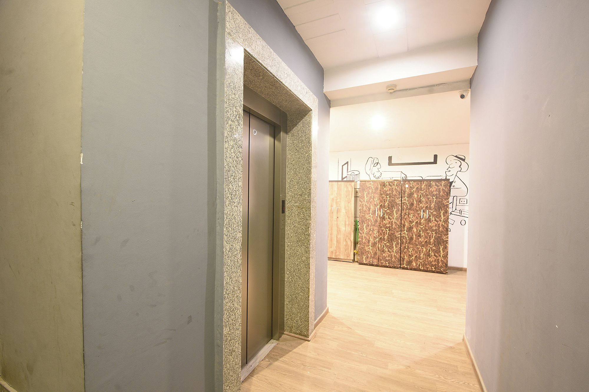A hallway with a door, a textured wall, and a wooden floor.