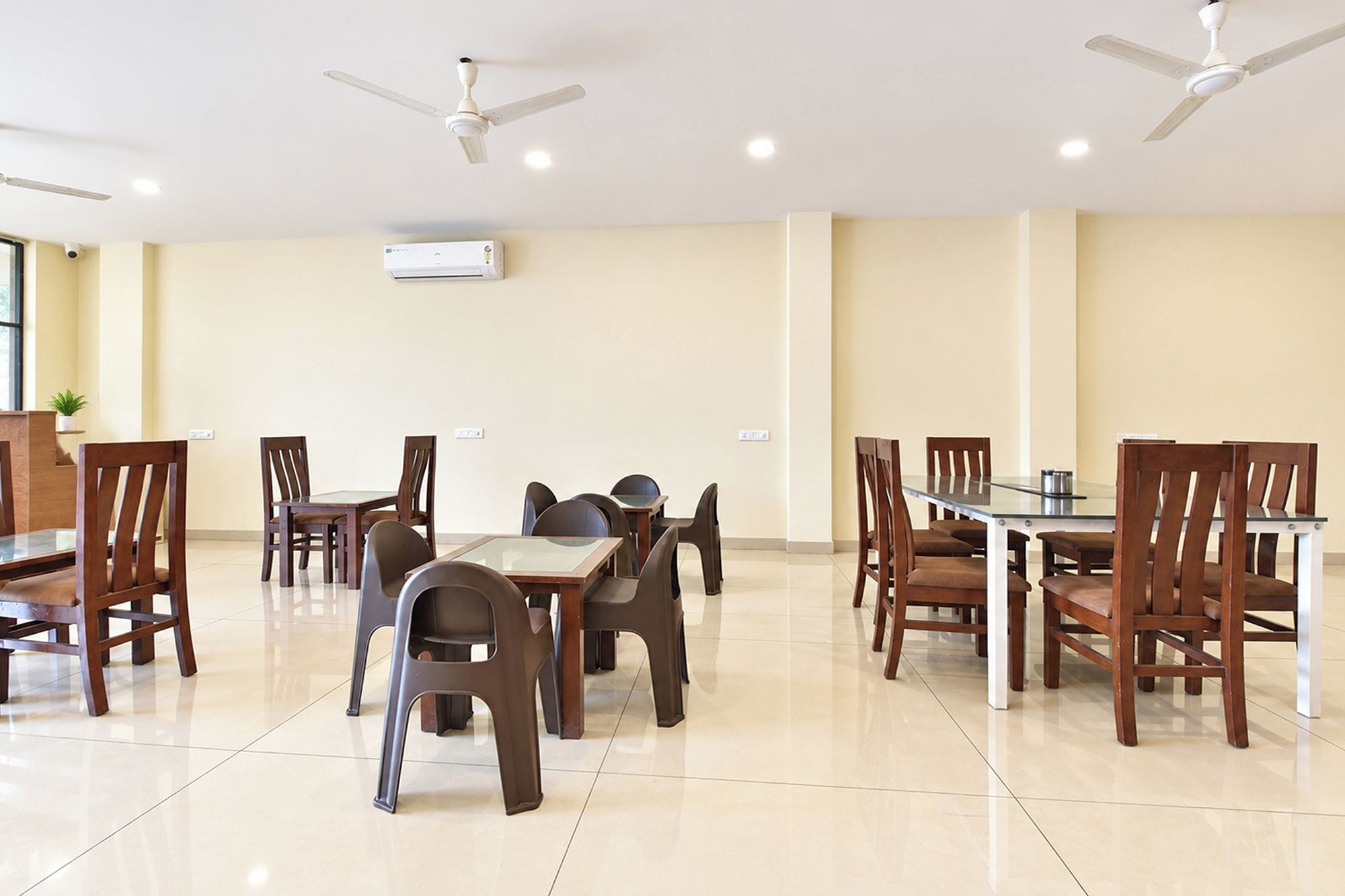 A dining area with multiple tables and chairs, ceiling fans, and an air conditioning unit.