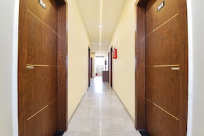 Un pasillo con puertas de madera, un extintor y suelo de baldosas.