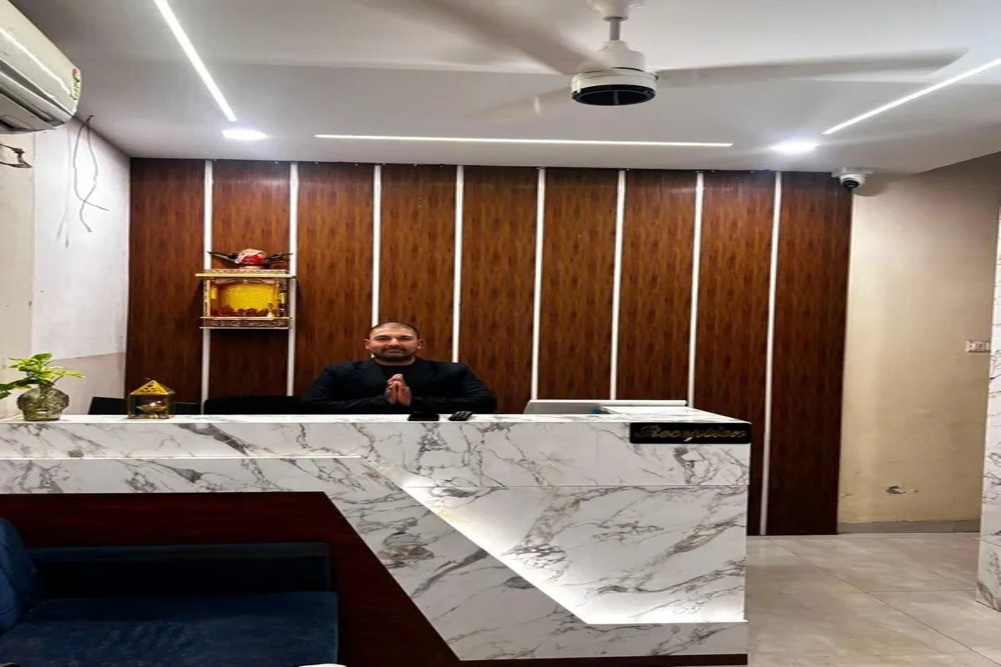 A reception desk with a marble top, a ceiling fan, and a wooden panel wall.
