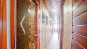A hallway with wooden paneling and a red door with a number sign. - Via Garden Inn (Mumbai)