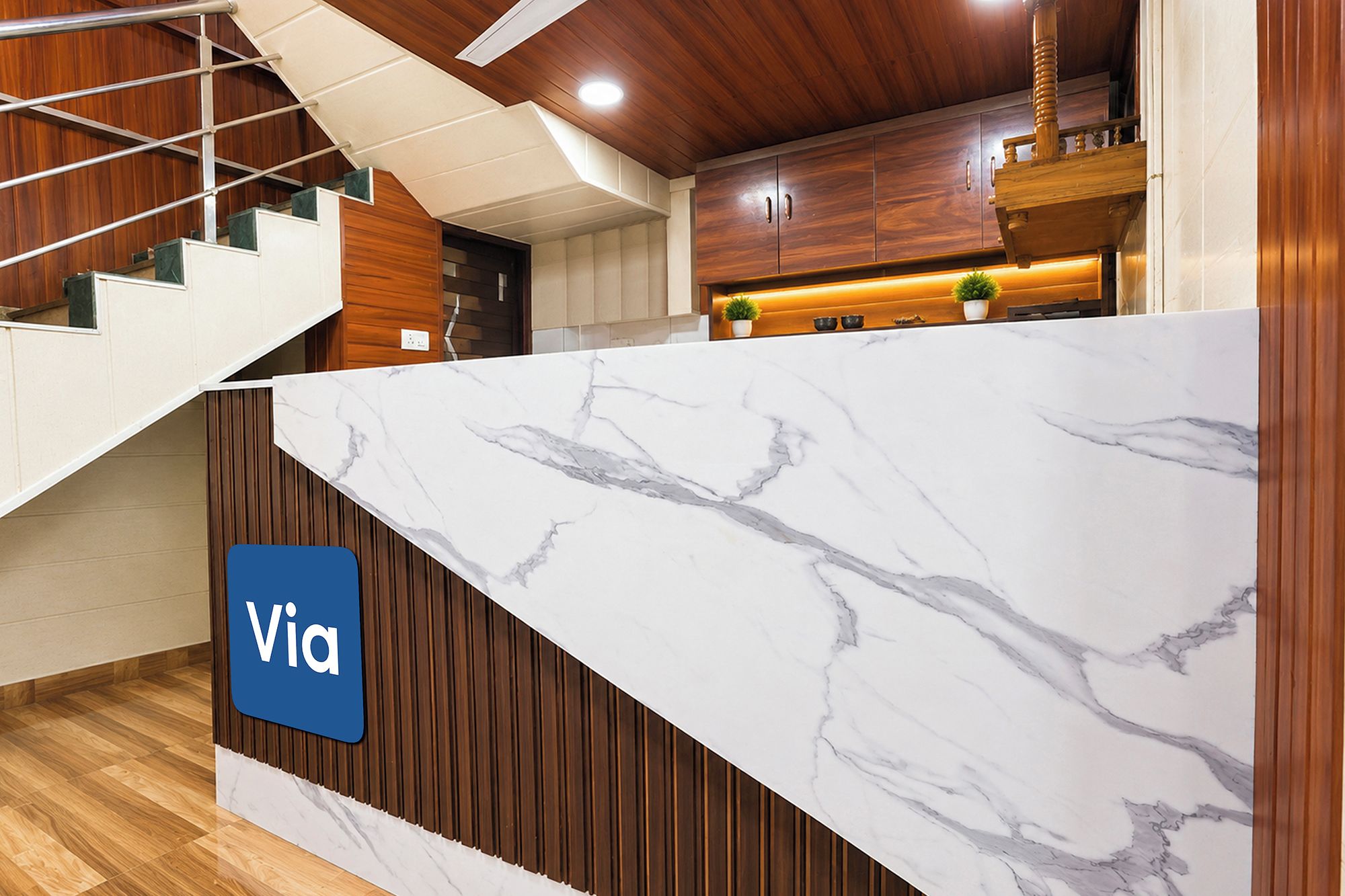 A modern kitchen with a marble countertop, wooden cabinets, and a staircase.