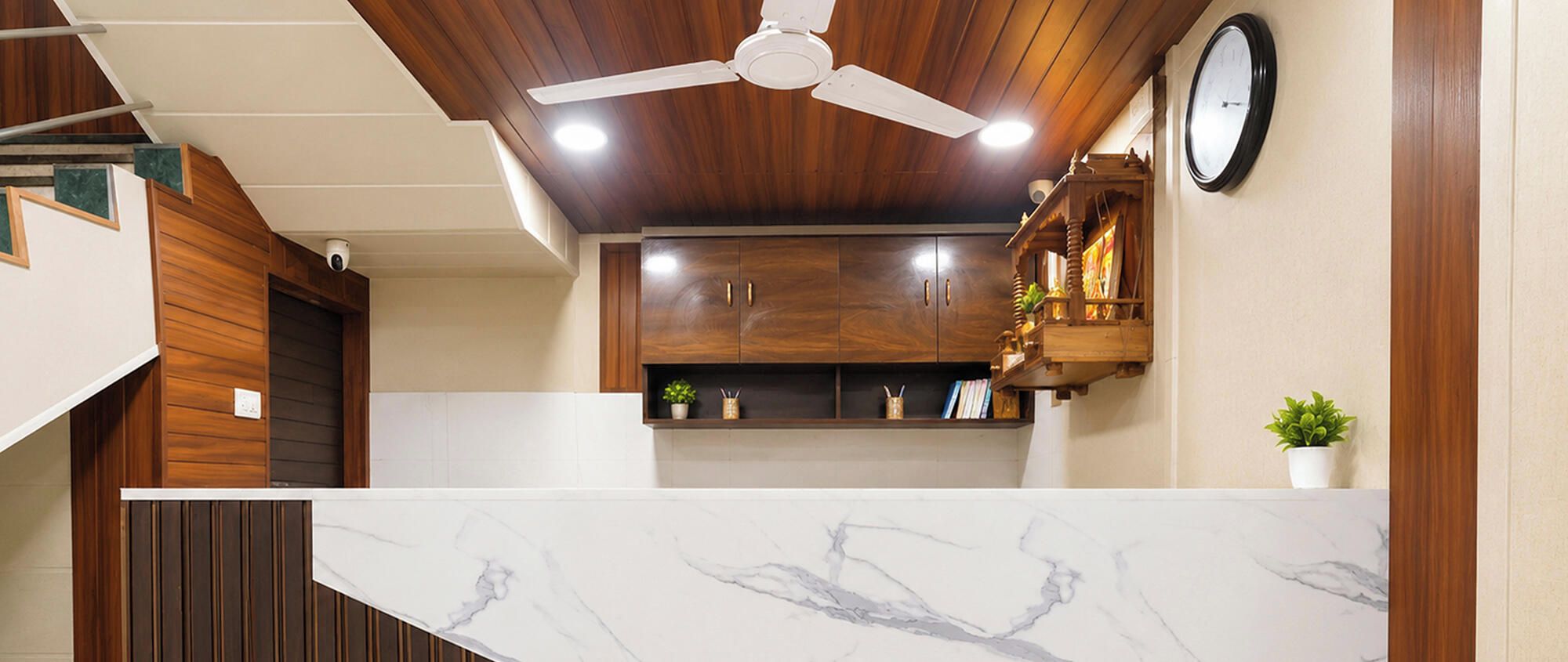 A kitchen with wooden cabinets, a marble countertop, and a ceiling fan.