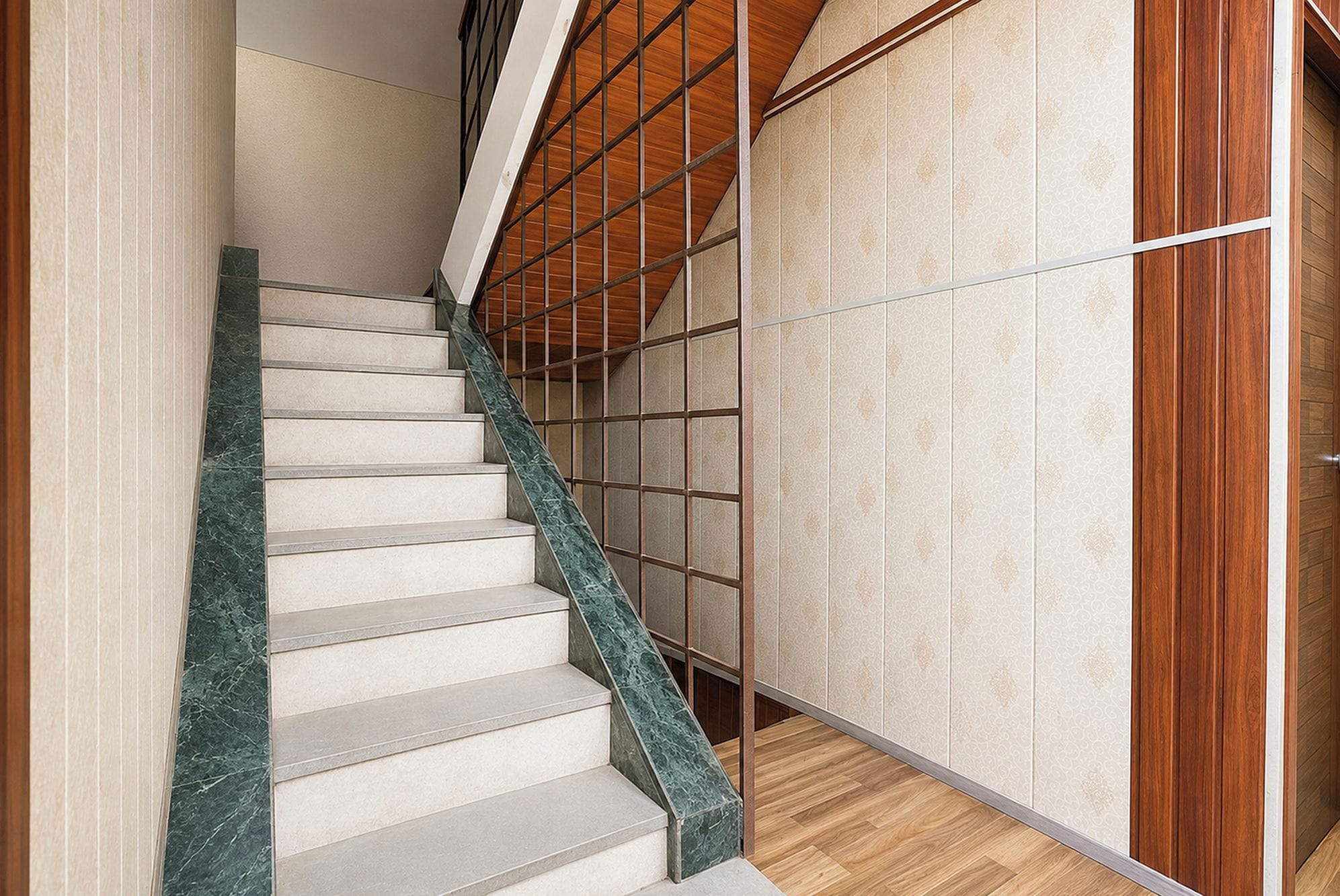 A staircase with a wooden handrail and a patterned wall.