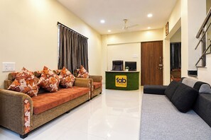 Un espace d’accueil d’hôtel comprenant un comptoir de réception, un canapé et un divan.