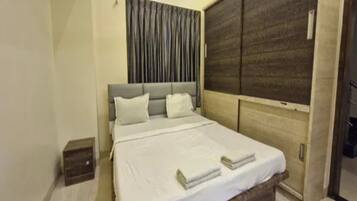 Un dormitorio con cama, mesita de noche, armario y ventana con cortinas.