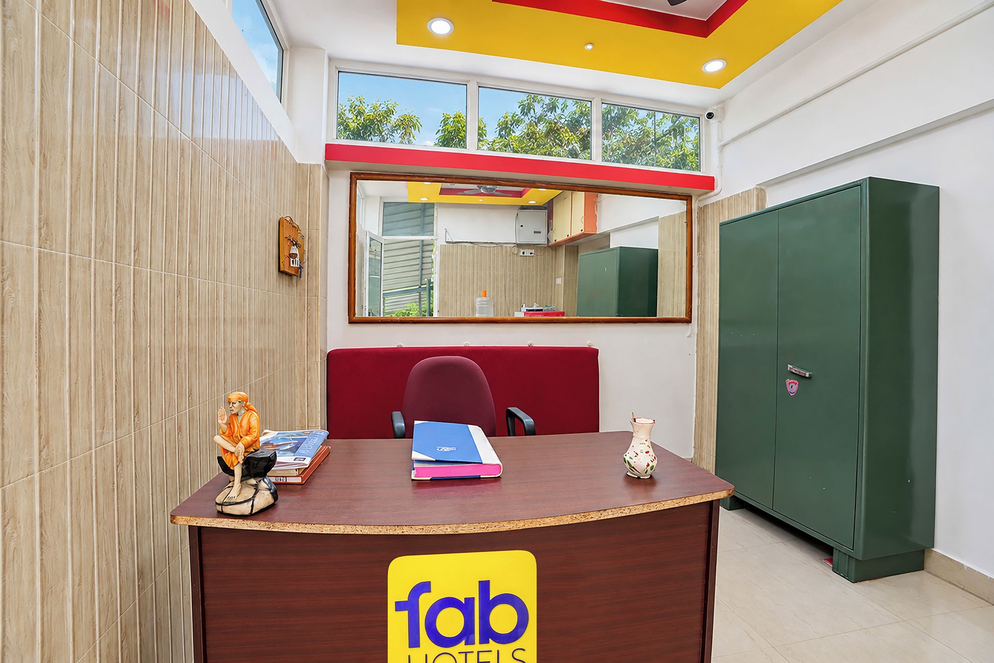 A reception desk with a 'fab hotels' sign, a mirror above it, and a green storage cabinet to the right.