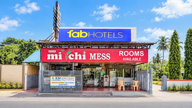 Un edificio con un letrero que dice 'fabHOTELS' y otro que indica 'mi chi mess' con la inscripción 'habitaciones disponibles'.