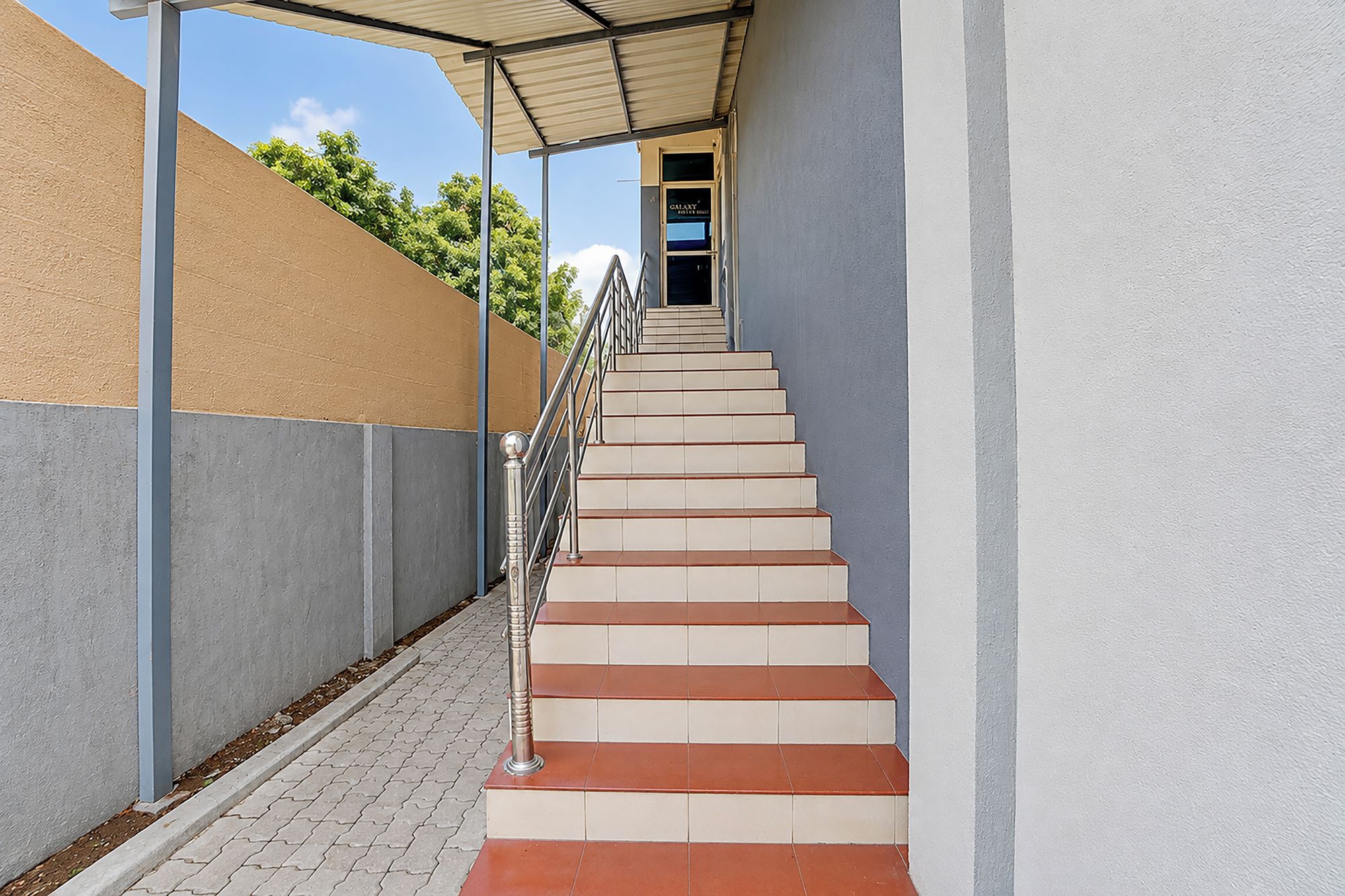 A staircase with a metal railing leading to a door with a sign above it.