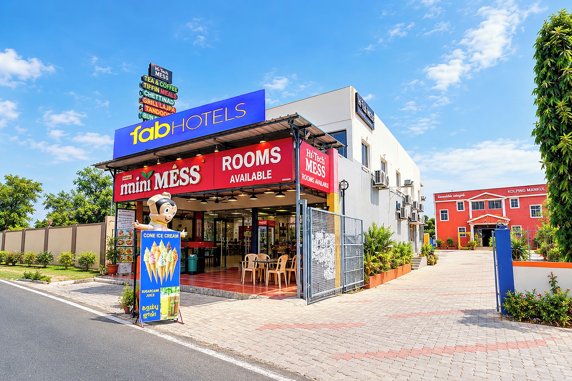 A hotel with a red and blue facade, a signboard advertising rooms, and a small outdoor seating area.