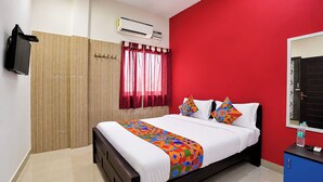 Habitación de hotel con una cama, armario, espejo y aire acondicionado.