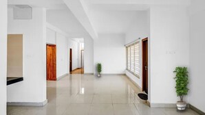 Un pasillo amplio con paredes blancas, una puerta de madera y una planta en maceta.